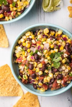 two bowls filled with black beans, corn and cilantro salsa next to tortilla chips