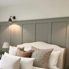 a bed with white linens and pillows in a small room next to a lamp