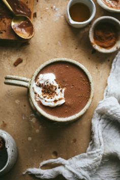 there is a cup of hot chocolate with whipped cream on top and spoons next to it