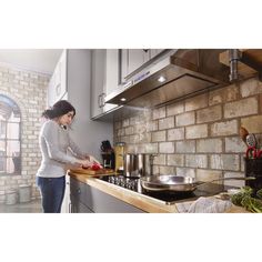 a woman standing in front of a stove preparing food on top of a wooden counter