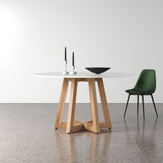 a white table with two green chairs and a black bowl on the top, in front of a white wall