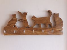 a wooden wall hanging with cats on it's sides and hooks in the middle