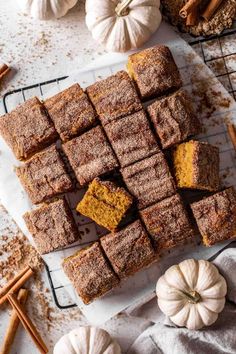 pumpkin spiced brownies on a cooling rack with cinnamon sticks and mini pumpkins in the background