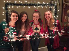 four girls holding up christmas lights in front of a mirror