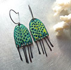 pair of earrings with green and black designs on them