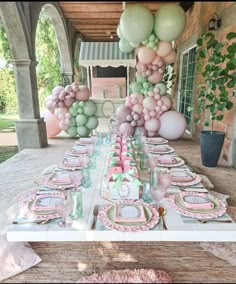 a table set up with pink and green balloons