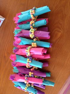 colorful candy wrappers are lined up on the floor with beads and paper bags attached to them