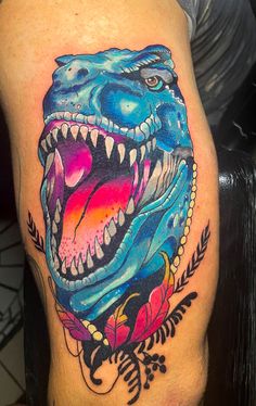 a colorful dinosaur tattoo on the thigh