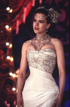 a woman in a white dress wearing a necklace and tiara with jewels on her head