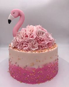 a pink flamingo cake with flowers and sprinkles on it's side