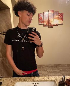 a young man taking a selfie in front of a bathroom mirror with his cell phone