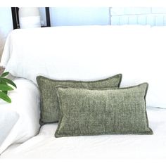 two pillows sitting on top of a white couch next to a potted green plant