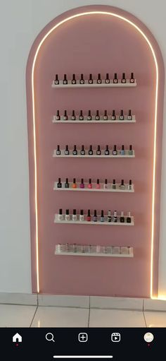 a pink wall with shelves filled with bottles and nail polishes on the top shelf