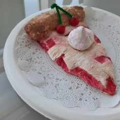 a piece of pie with whipped cream and cherries sits on a lace doily