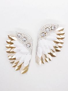 two white and gold leaf shaped brooches with pearls on the ends, one is attached