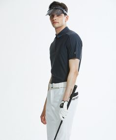 a man in black shirt and white pants holding a golf club