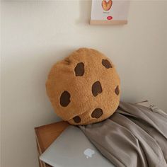 a stuffed cookie sitting on top of an apple laptop computer next to a wall hanging