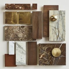 several different types of marbles and wood are arranged on a white surface with gold accents