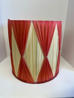 a large red and white vase sitting on top of a table next to a wall