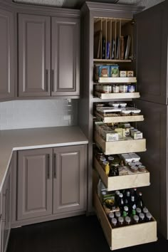 an organized pantry in a kitchen with gray cabinets and white counter tops, along with pull out drawers