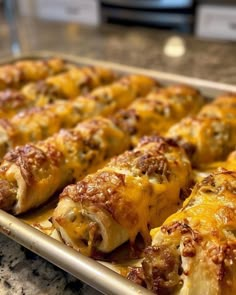 a baking pan filled with cheesy bread covered in cheese and sauce, sitting on a kitchen counter