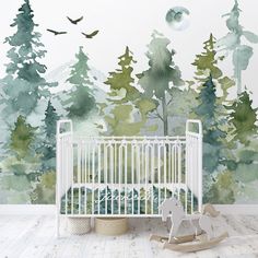 a baby's room with a crib and trees painted on the wall behind it