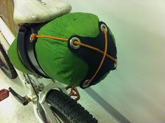 a green bag sitting on the back of a bike