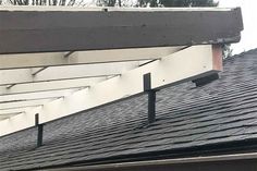 a black and white cat sitting on top of a roof next to a building with an awning