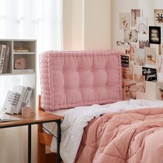 a bed with pink comforter and pillows in a bedroom next to a book shelf