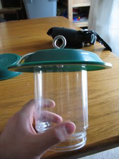 a person holding a glass with a green lid