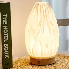 a white lamp sitting on top of a table next to a book