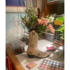 a pair of boots sitting on top of a counter next to flowers and paintbrushes