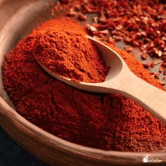 a wooden spoon filled with red powder and spices