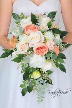 a bride holding a bouquet of white and peach flowers on her wedding day in front of a window