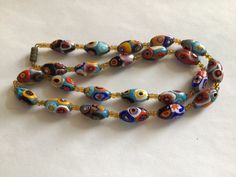 "This long necklace of handmade millefiori glass beads and cut crystal beads gives a fresh fashion spin to your boho look, your jeans or your little black dress. Ravishing color is fused in these oval beads blues, red, orange, greens, aqua and sun yellow. Faceted link chain and metal accents are finished in bronze. Millefiori means \"thousand flowers.\" Bundles of tiny glass filament rods are sliced, then fired to meld their brilliant colors and floral patterns. No two beads are ever identical." Bohemian Handmade Murano Glass Necklaces, Bohemian Murano Glass Beads, Colorful, Bohemian Handmade Murano Glass Necklace, Bohemian Murano Glass Colorful Beads, Bohemian Colorful Murano Glass Beads, Handmade Bohemian Murano Glass Beaded Necklaces, Bohemian Murano Glass Beaded Necklaces, Bohemian Murano Glass Beaded Necklace, Sun Yellow