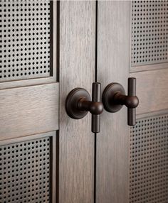 a close up of the handles on a wooden door with perforated metal panels