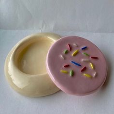 a pink doughnut with sprinkles sitting on top of a white table