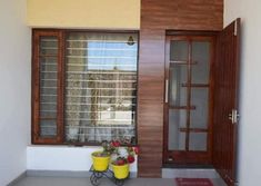 two flower pots sitting on the floor in front of a window with wooden doors and windowsills