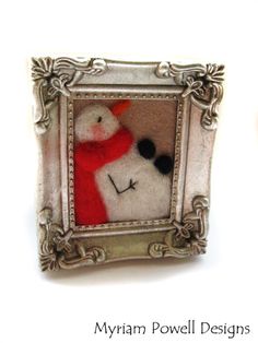 a white and red snowman in a silver frame on a white background with the words, myrian powell designs