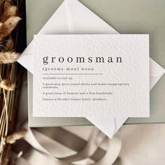 an envelope with the word groomsman on it next to some dry grass and flowers