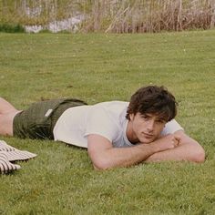 a man laying on the grass with his arms crossed