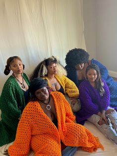 four women sitting on a bed in colorful clothing