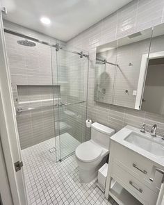 a white toilet sitting next to a bathroom sink under a mirror and walk in shower