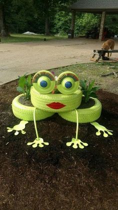 a green frog statue sitting on top of a pile of dirt