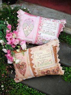 two pillows sitting on the ground next to flowers