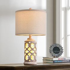 a table with a lamp on top of it and some books next to the lamp