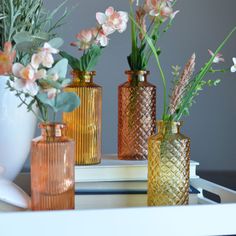 three vases with flowers in them sitting on a table