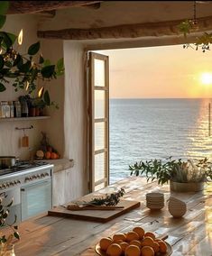 a kitchen with an open window overlooking the ocean at sunset or sun set over the water