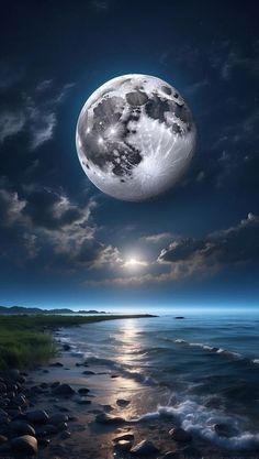 the full moon is shining brightly over the water and rocks on the shore at night