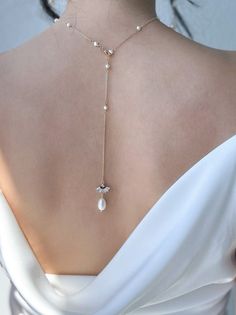 the back of a woman's neck wearing a necklace with pearls and a star